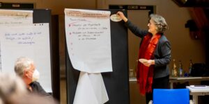 Workshop zur Entwicklung der AmperWoGe: Teilnehmerin erläutert Themen und Ergebnisse am Flipchart während einer gemeinsamen Arbeitsrunde.