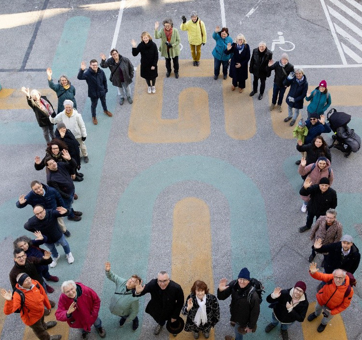 Gruppenfoto der AmperWoGe: Mitglieder formen ein Haus als Symbol für Gemeinschaft, bezahlbaren Wohnraum und Zusammenhalt in der AmperWoGe.