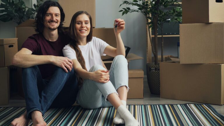 Paar, das den Schlüssel für eine bezalbare Wohnung hoch hält